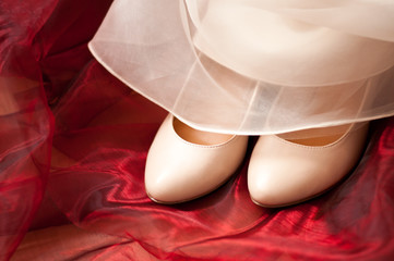 Fototapeta na wymiar Buty ślubne i suknia ślubna na czerwonym tkaniny
