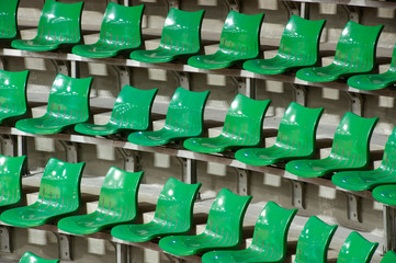 Plenty of green plastic seats at stadium .