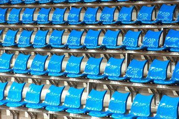 Plenty of  blue plastic seats at stadium .