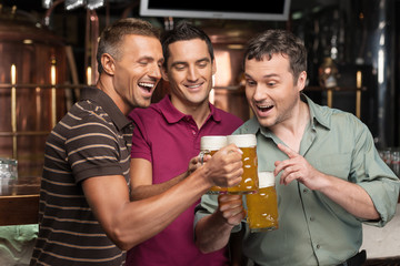 Old friends. Three happy friends drinking beer at the pub