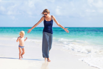 Mother and little daughter walking on the beach