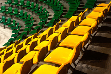 Plenty of yellow and green plastic seats at stadium .