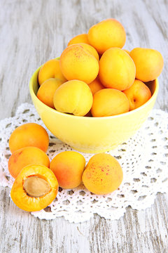 Fresh natural apricot in bowl on green wooden table