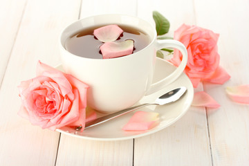 cup of tea with roses on white wooden table