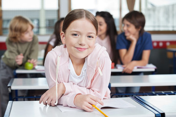 Schoolgirl Smiling While Leaning On Desk