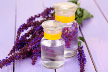 Medicine bottles with salvia flowers on purple wooden