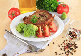 Piece of fried meat on plate on wooden table close-up
