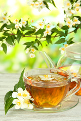 Cup of tea with jasmine, on wooden table, on bright background