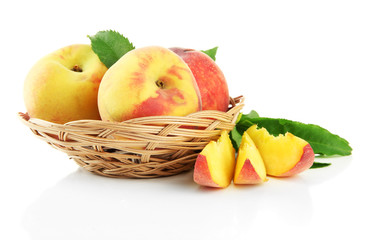 Ripe sweet peaches with leaves in basket, isolated on white