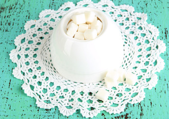 Refined sugar in white sugar bowl on wooden background