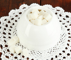 Refined sugar in white sugar bowl on wooden background