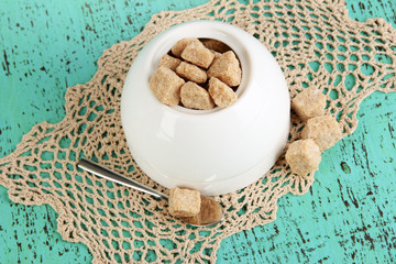 Unrefined sugar in white sugar bowl on wooden background