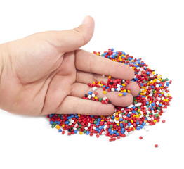 Colorful plastic polymer granules and man hand on white