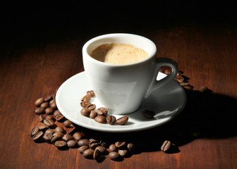 Cup of coffee with coffee beans on wooden background