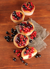 Tasty muffins with berries on wooden table