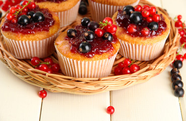 Tasty muffins with berries on white wooden table