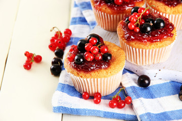 Tasty muffins with berries on white wooden table