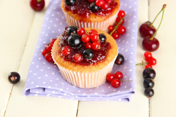 Tasty muffins with berries on white wooden table