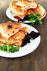 Pizza calzone on plates on wooden table