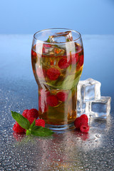 Iced tea with raspberries and mint on blue background