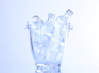 Minibar bottles in bucket with ice cubes, isolated on white