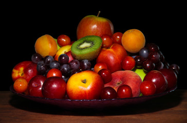 Assortment of juicy fruits on wooden table, on  dark background