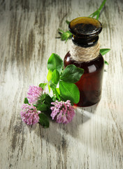 Medicine bottle with clover flowers on wooden table