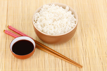 Bowl of rice and chopsticks on bamboo mat