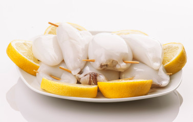 raw squid stuffed ready to be cooked in plate and cut lemons