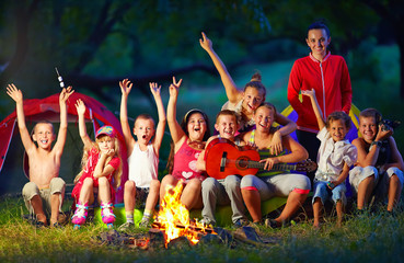 happy kids singing songs around camp fire