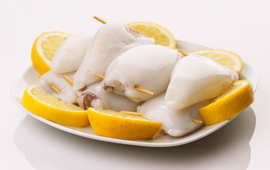 raw squid stuffed ready to be cooked in plate and cut lemons