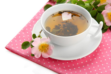 Cup of herbal tea with hip rose flowers, isolated on white
