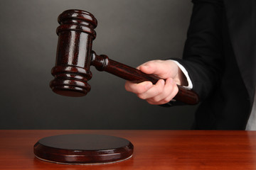 Judge's gavel in hand on grey background