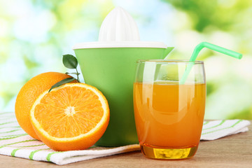 Citrus press, glass of juice and ripe oranges