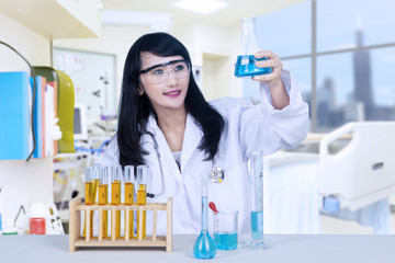 Fototapeta premium Beautiful female doctor analysing chemical in hospital