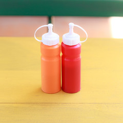 bottle of chili and tomato sauce on yellow table