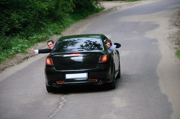 Fototapeta na wymiar happy newlyweds traveling in a car and wave hands