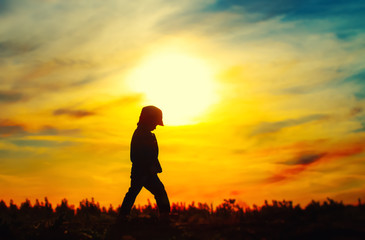 Young silhouetted child at sunset sky