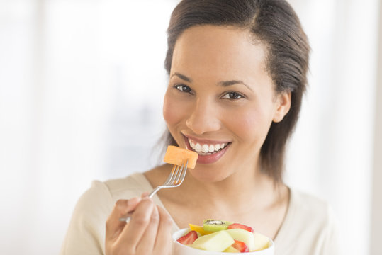 Woman Eating Fresh Fruit Salad At Home