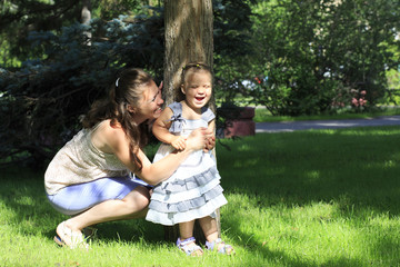 Fototapeta premium Joyful mother with a young daughter playing in a city park.