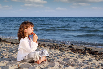little girl play pan pipe on beach