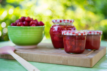 Homemade strawberry jam in different jars and fresh ripe strawbe