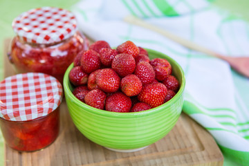 Homemade strawberry jam in different jars and fresh ripe strawbe