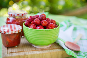 Homemade strawberry jam in different jars and fresh ripe strawbe