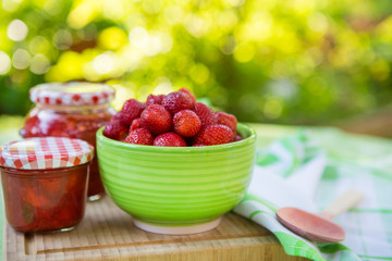 Homemade strawberry jam in different jars and fresh ripe strawbe
