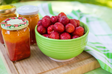 Homemade strawberry jam in different jars and fresh ripe strawbe