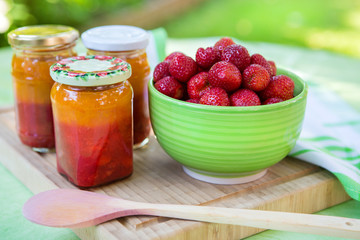 Homemade strawberry jam in different jars and fresh ripe strawbe