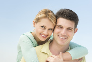 Woman Embracing Man From Behind Against Clear Blue Sky