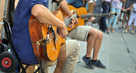 artisti di strada con chitarra, con pubblico sullo sfondo
