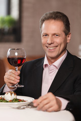 Only the best wine. Confident men in formal wear holding a glass